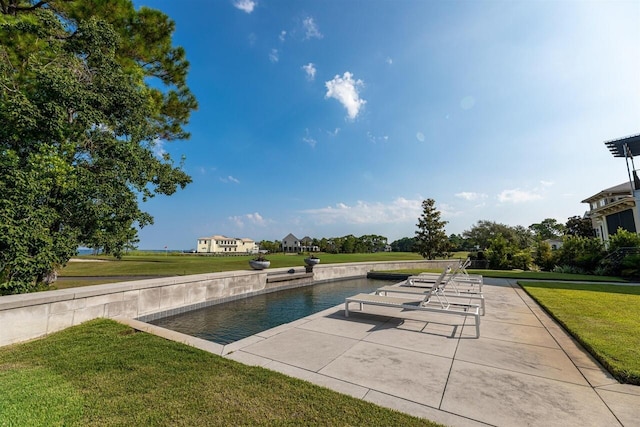 view of pool with a patio and a lawn