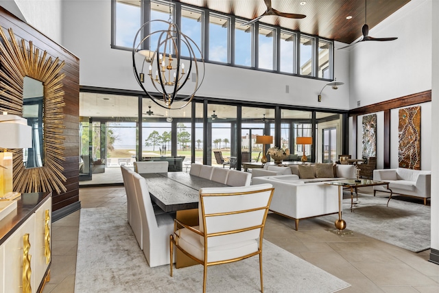 interior space featuring ceiling fan with notable chandelier, light tile flooring, a healthy amount of sunlight, and a high ceiling