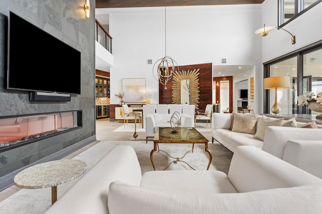 living room featuring a tile fireplace, a chandelier, and a high ceiling