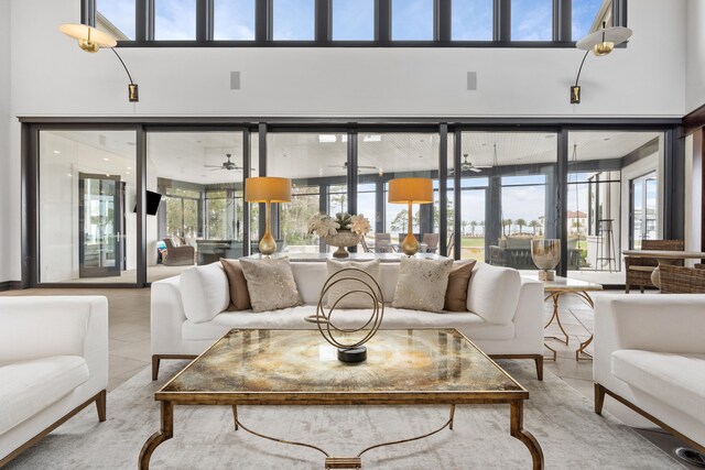 living room with ceiling fan, light tile flooring, and a towering ceiling