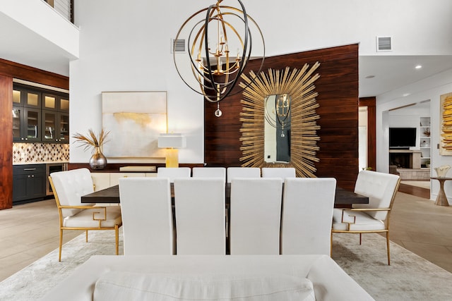 dining room featuring a notable chandelier, wood walls, light tile floors, and a fireplace