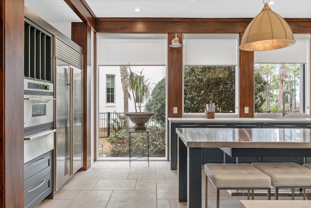 kitchen with a kitchen breakfast bar, stainless steel appliances, sink, and decorative light fixtures