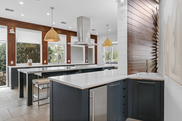 kitchen featuring island exhaust hood, gray cabinets, decorative light fixtures, and sink