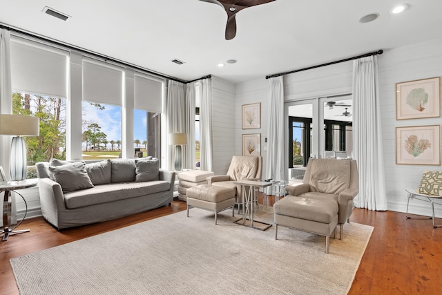 living room featuring a wealth of natural light, dark wood-type flooring, ceiling fan, and french doors