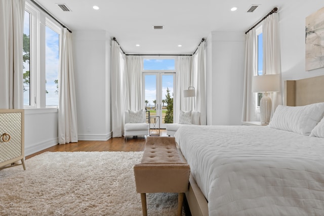 bedroom featuring french doors, light hardwood / wood-style flooring, and multiple windows