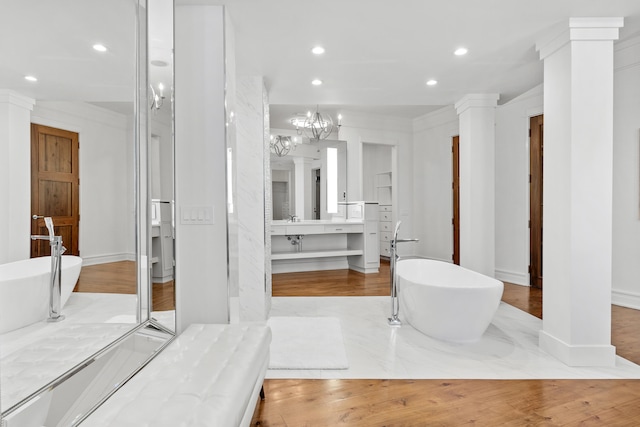 bathroom with crown molding, vanity, a notable chandelier, and a tub