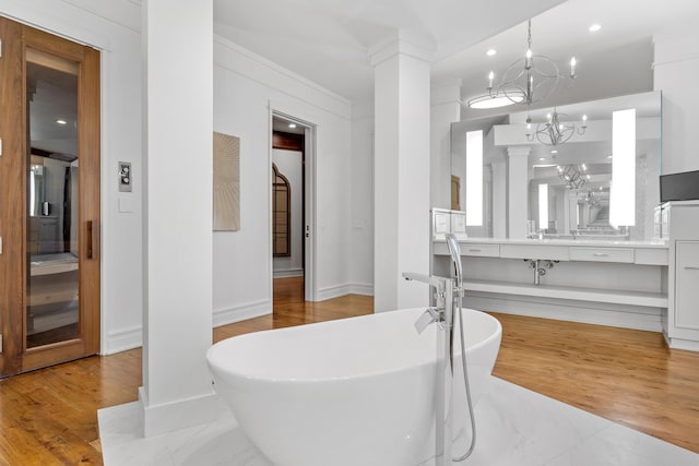 bathroom featuring a tub, hardwood / wood-style floors, vanity, and a chandelier