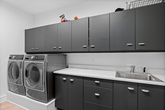 washroom featuring light hardwood / wood-style flooring, cabinets, independent washer and dryer, and sink