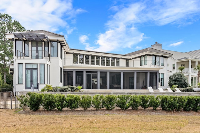 back of house featuring a balcony, a sunroom, and a lawn