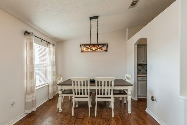 dining space with a textured ceiling, dark hardwood / wood-style flooring, and vaulted ceiling