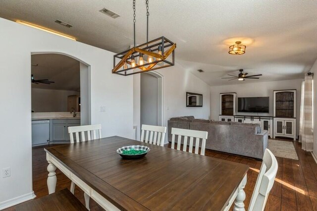 dining space with sink, vaulted ceiling, ceiling fan, a textured ceiling, and dark hardwood / wood-style flooring