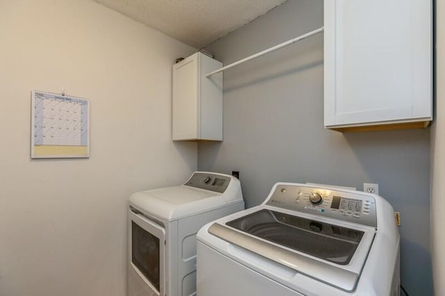 washroom with cabinets, separate washer and dryer, and a textured ceiling