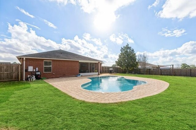 view of swimming pool featuring a lawn, a sunroom, and a patio