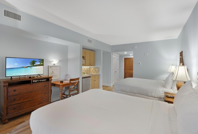 bedroom with ensuite bathroom and light wood-type flooring