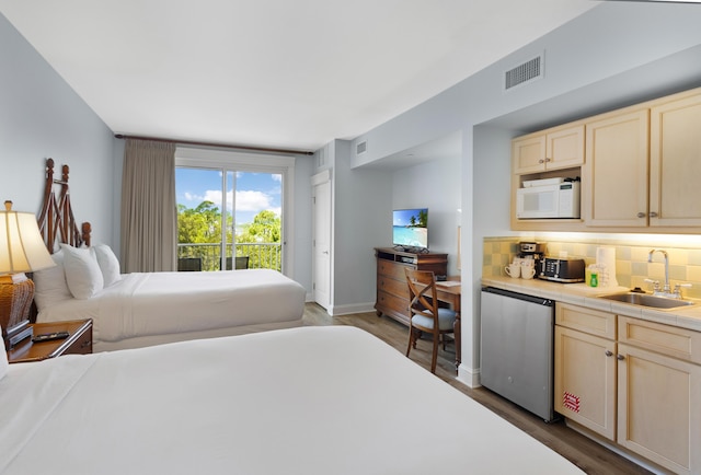 bedroom with access to exterior, sink, and hardwood / wood-style flooring