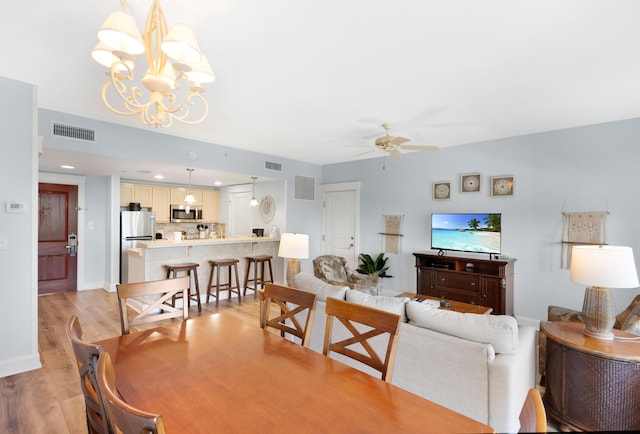 dining room featuring ceiling fan with notable chandelier and light hardwood / wood-style floors