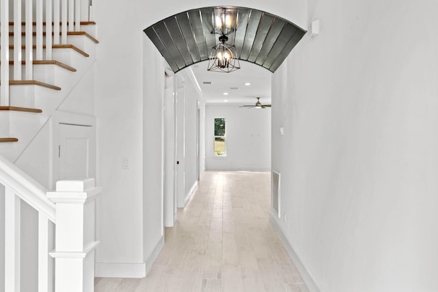 hall with light wood-type flooring and a chandelier