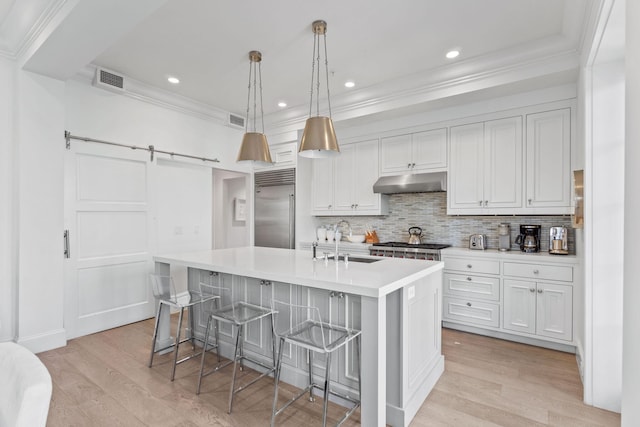 kitchen with appliances with stainless steel finishes, light hardwood / wood-style flooring, sink, and a kitchen island with sink