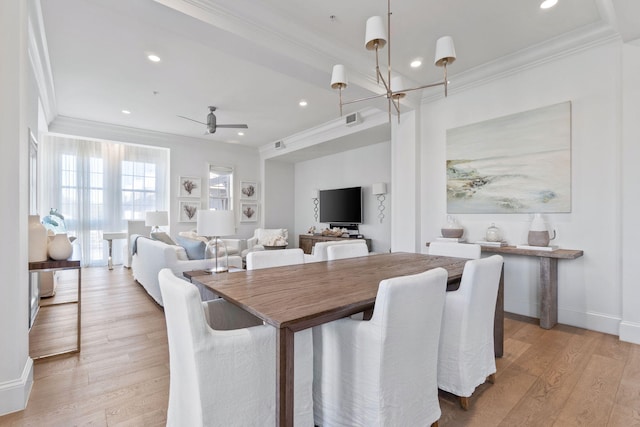 dining area featuring ceiling fan with notable chandelier, crown molding, and light wood-type flooring