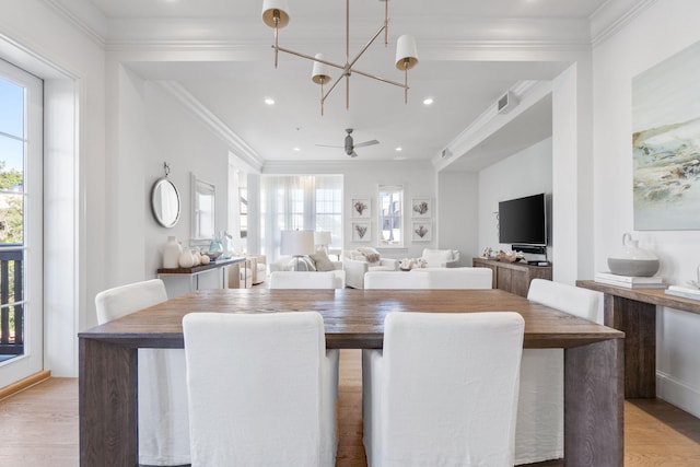 dining area featuring ceiling fan with notable chandelier, light hardwood / wood-style floors, and ornamental molding