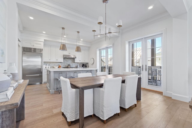 dining room featuring ornamental molding, light hardwood / wood-style floors, french doors, and an inviting chandelier