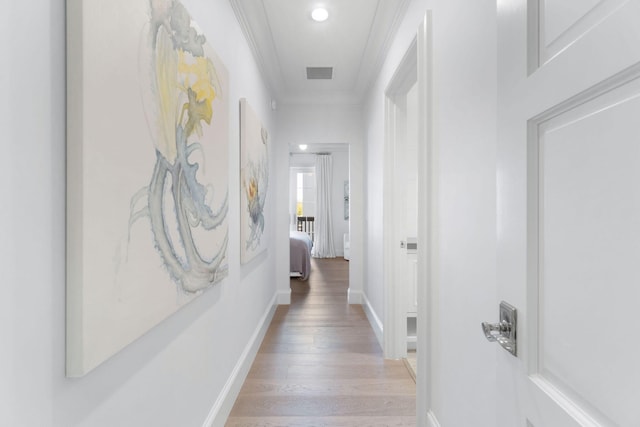 hallway featuring ornamental molding and light hardwood / wood-style flooring