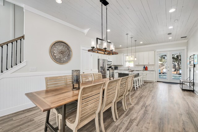 dining space with sink, french doors, crown molding, and light hardwood / wood-style flooring