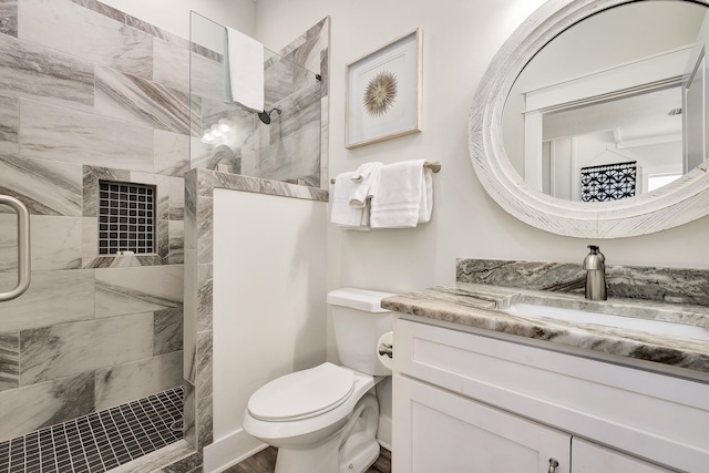 bathroom featuring toilet, vanity, and a tile shower