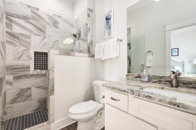 bathroom featuring tiled shower, vanity with extensive cabinet space, and toilet