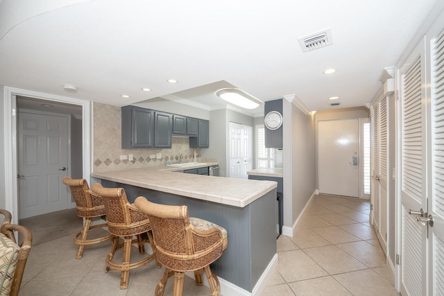 kitchen with light tile patterned flooring, a peninsula, visible vents, backsplash, and a kitchen bar