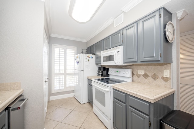 kitchen with white appliances, tasteful backsplash, light tile patterned floors, crown molding, and gray cabinetry