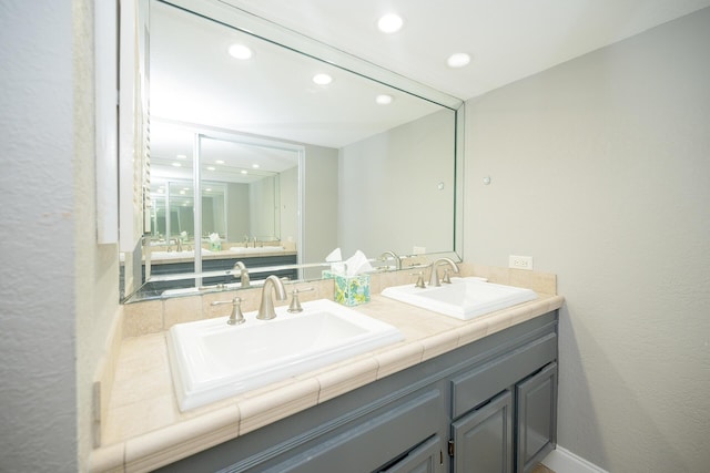 full bath with double vanity, a sink, and recessed lighting