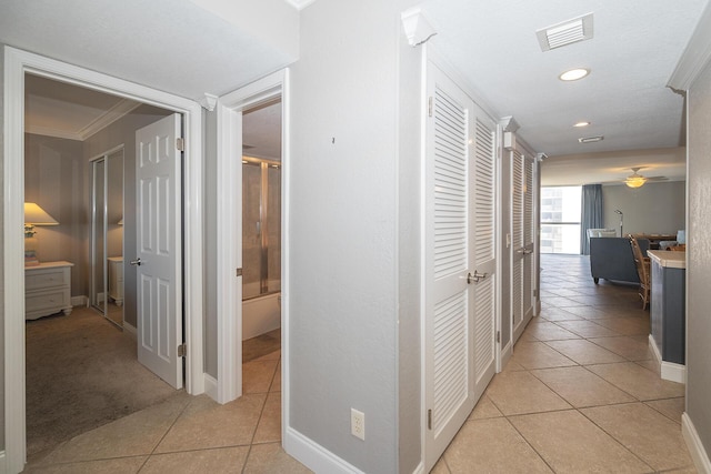 hall featuring light tile patterned floors, ornamental molding, visible vents, and baseboards