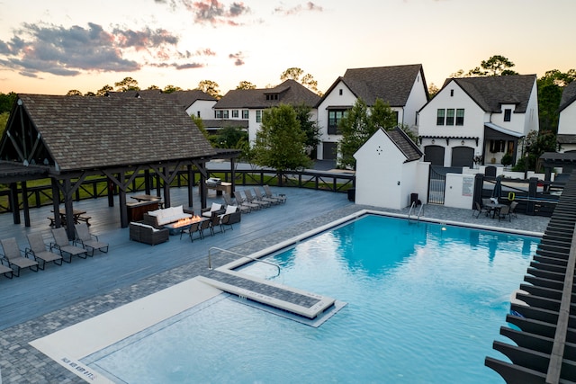 pool at dusk featuring a patio area and a gazebo