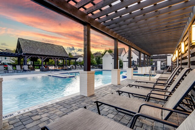 pool at dusk featuring a pergola, a gazebo, and a patio area