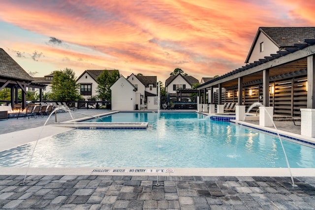 pool at dusk with a patio and pool water feature