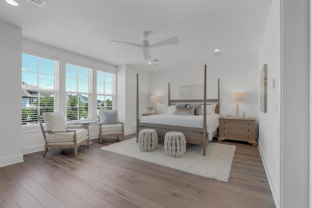 bedroom with hardwood / wood-style floors, ceiling fan, and multiple windows