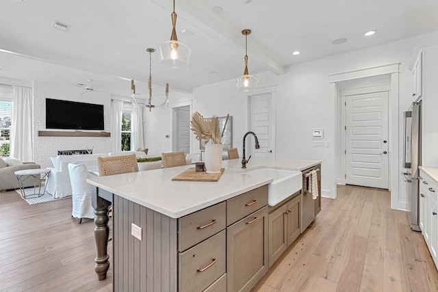 kitchen featuring white cabinets, sink, an island with sink, and light wood-type flooring