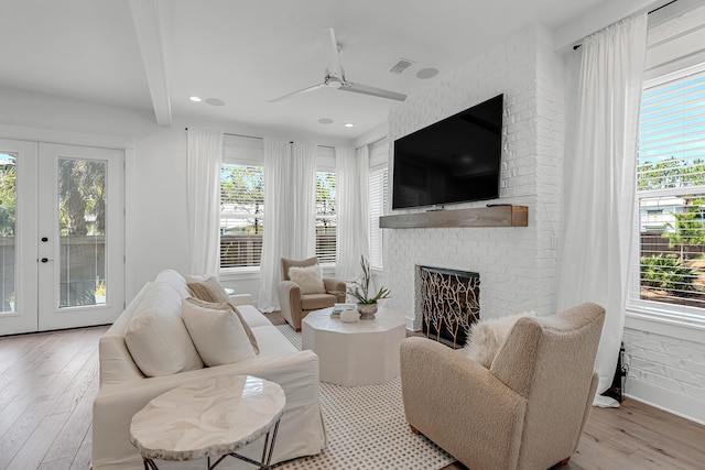 living room featuring ceiling fan, light hardwood / wood-style floors, french doors, and a brick fireplace