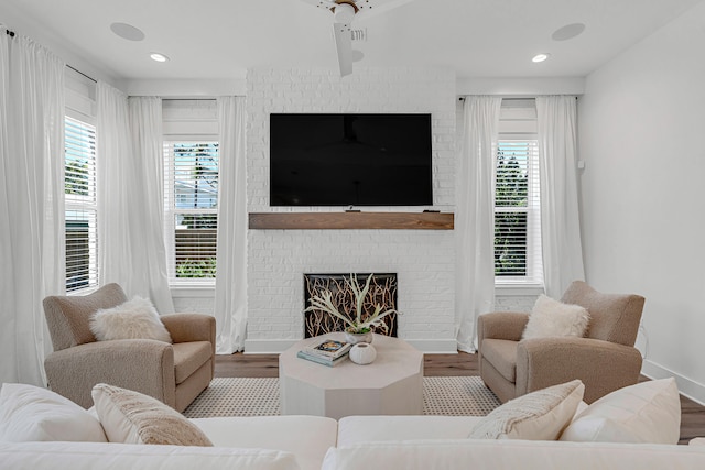 living room featuring wood-type flooring, a fireplace, plenty of natural light, and ceiling fan