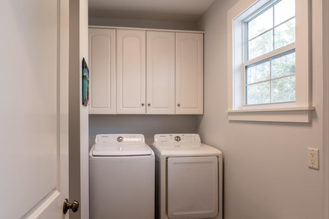 clothes washing area featuring cabinets and washer and clothes dryer