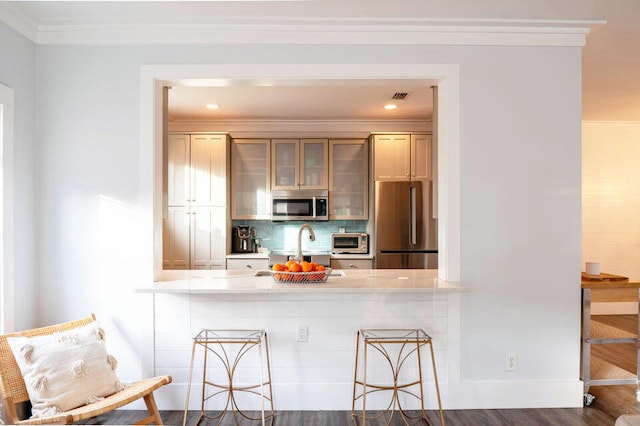 kitchen with a kitchen breakfast bar, crown molding, dark hardwood / wood-style flooring, backsplash, and stainless steel appliances