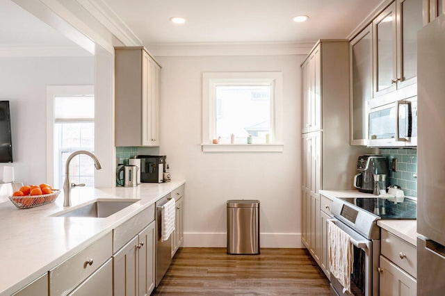 kitchen with appliances with stainless steel finishes, light hardwood / wood-style flooring, sink, and backsplash