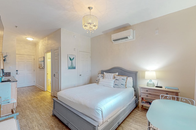 bedroom featuring a wall unit AC, an inviting chandelier, and light wood-type flooring