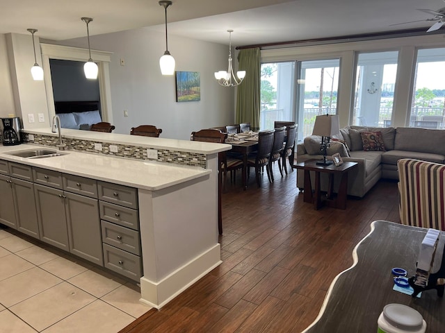 kitchen featuring sink, hanging light fixtures, kitchen peninsula, light hardwood / wood-style floors, and gray cabinets