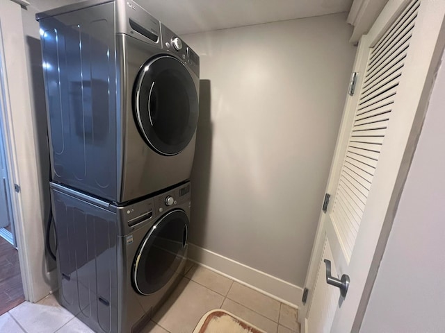 washroom with light tile patterned floors, laundry area, stacked washer and clothes dryer, and baseboards