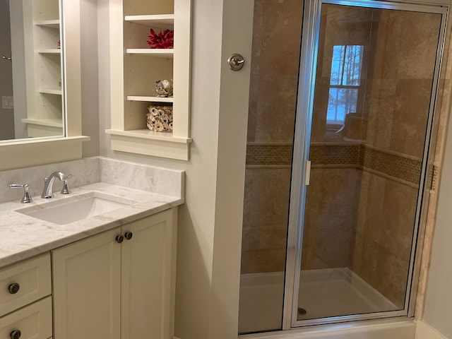 bathroom with built in shelves, a shower stall, and vanity