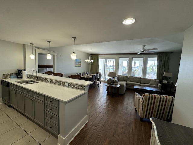 kitchen with pendant lighting, gray cabinetry, open floor plan, a sink, and dishwashing machine