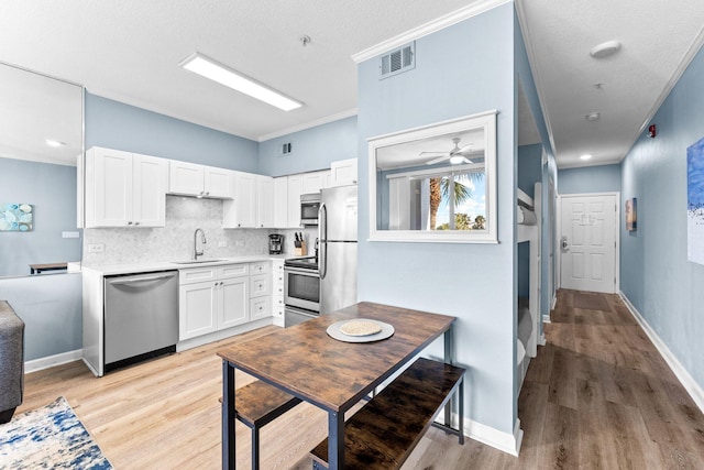 kitchen with white cabinets, appliances with stainless steel finishes, ceiling fan, and light hardwood / wood-style flooring