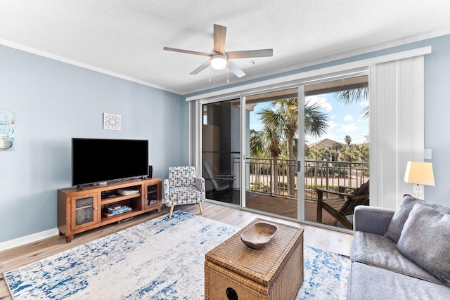 living room featuring ornamental molding, ceiling fan, light wood-type flooring, and a textured ceiling